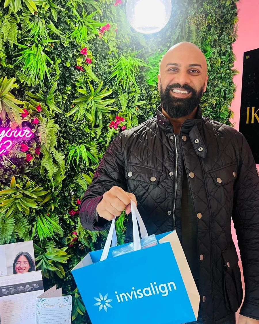 Delighted Patient at Foliage Wall with Clear Aligners